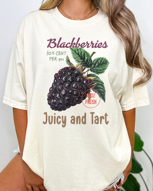 Woman wearing a 'Blackberries - Juicy And Tart' shirt in natural beige, featuring a retro blackberry commercial graphic design and unisex fit.