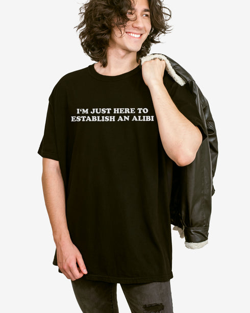 Man wearing a black I'm Just Here To Establish An Alibi shirt.