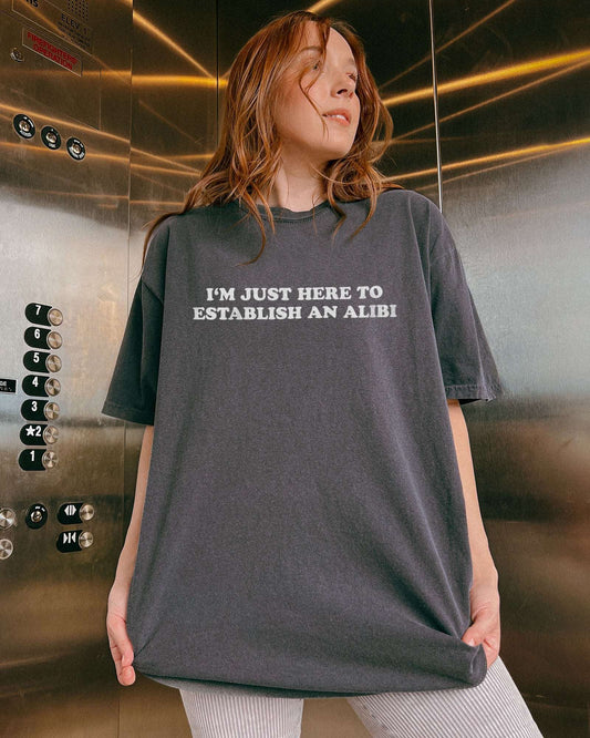 Woman wearing a pepper I'm Just Here To Establish An Alibi shirt.