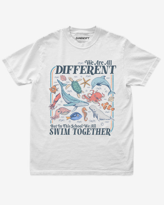 Flat lay of white We Are All Different But In This School We All Swim Together Shirt with cute retro ocean animal design