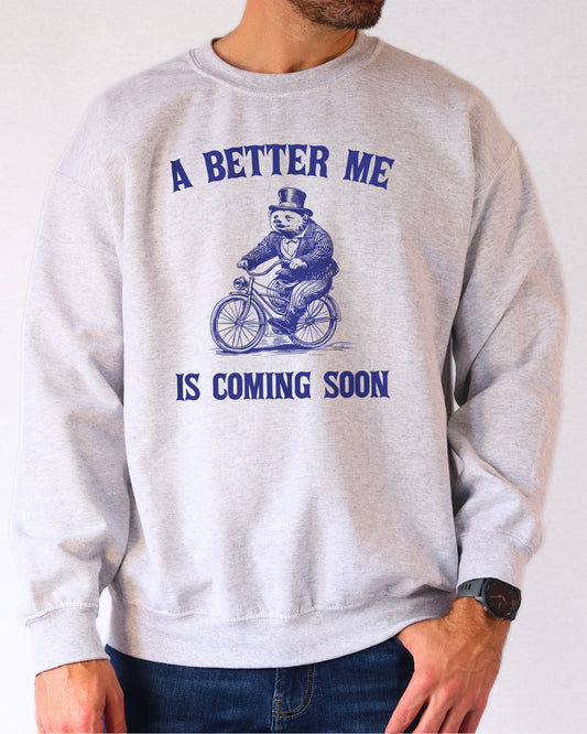 Model wearing ash color sweatshirt with 'A Better Me Is Coming' graphic design
