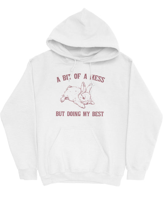 Flat lay of a white hoodie featuring the phrase 'A Bit Of A Mess But Doing My Best' with a retro bunny line art graphic.