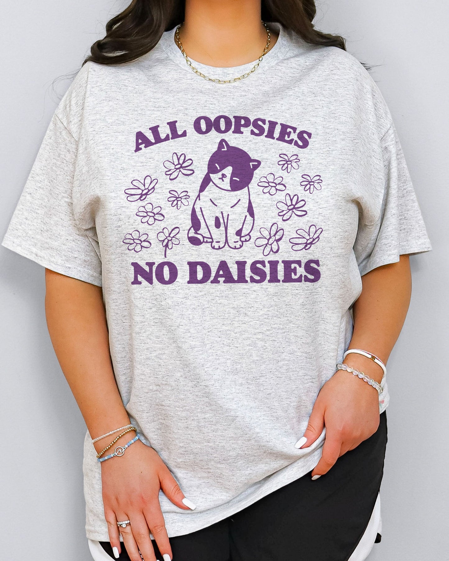 Model wearing ash color shirt with 'All Oopsies No Daisies' graphic design