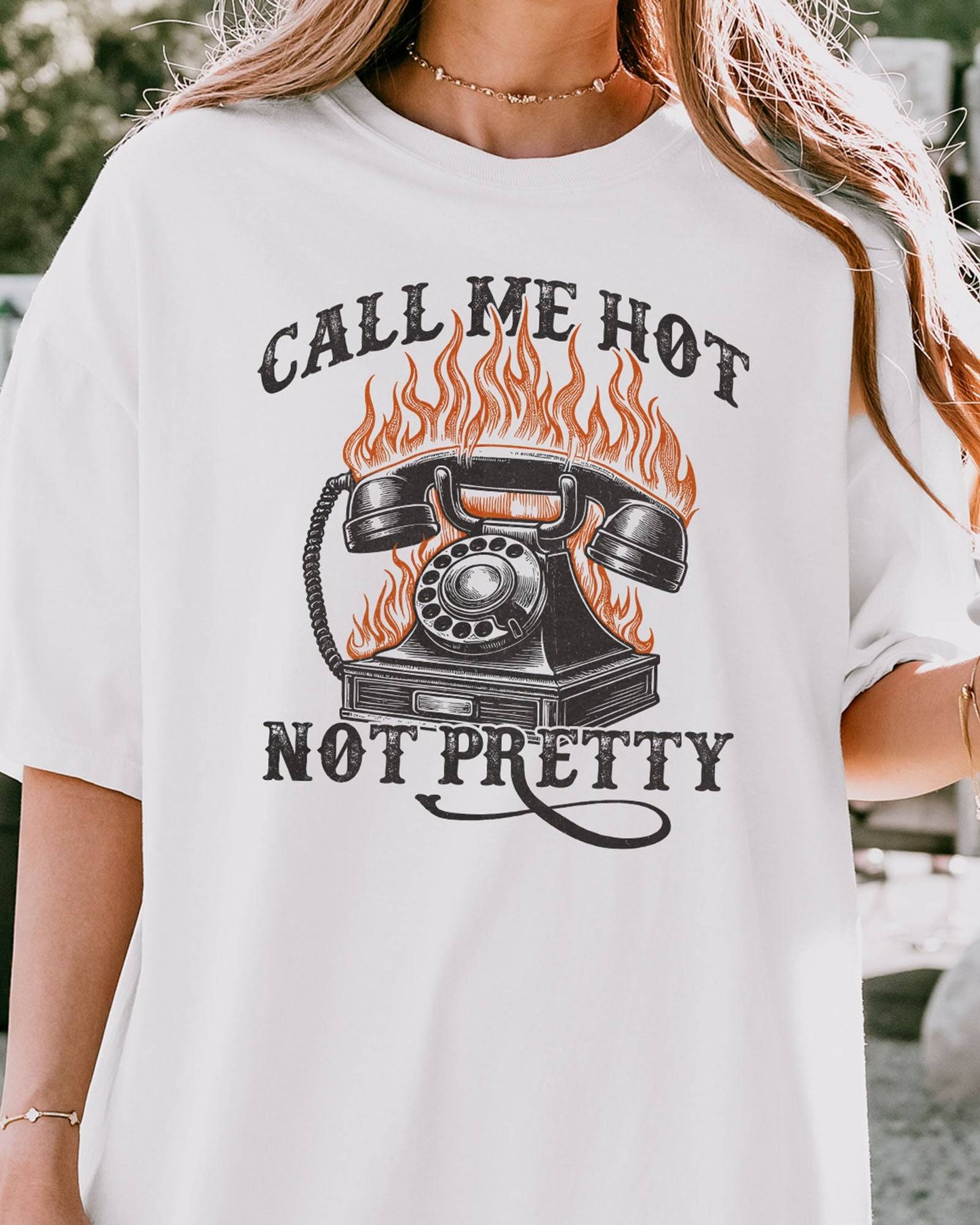 Close-up of woman wearing a white 'Call Me Hot Not Pretty' shirt with a retro graphic of a burning phone.