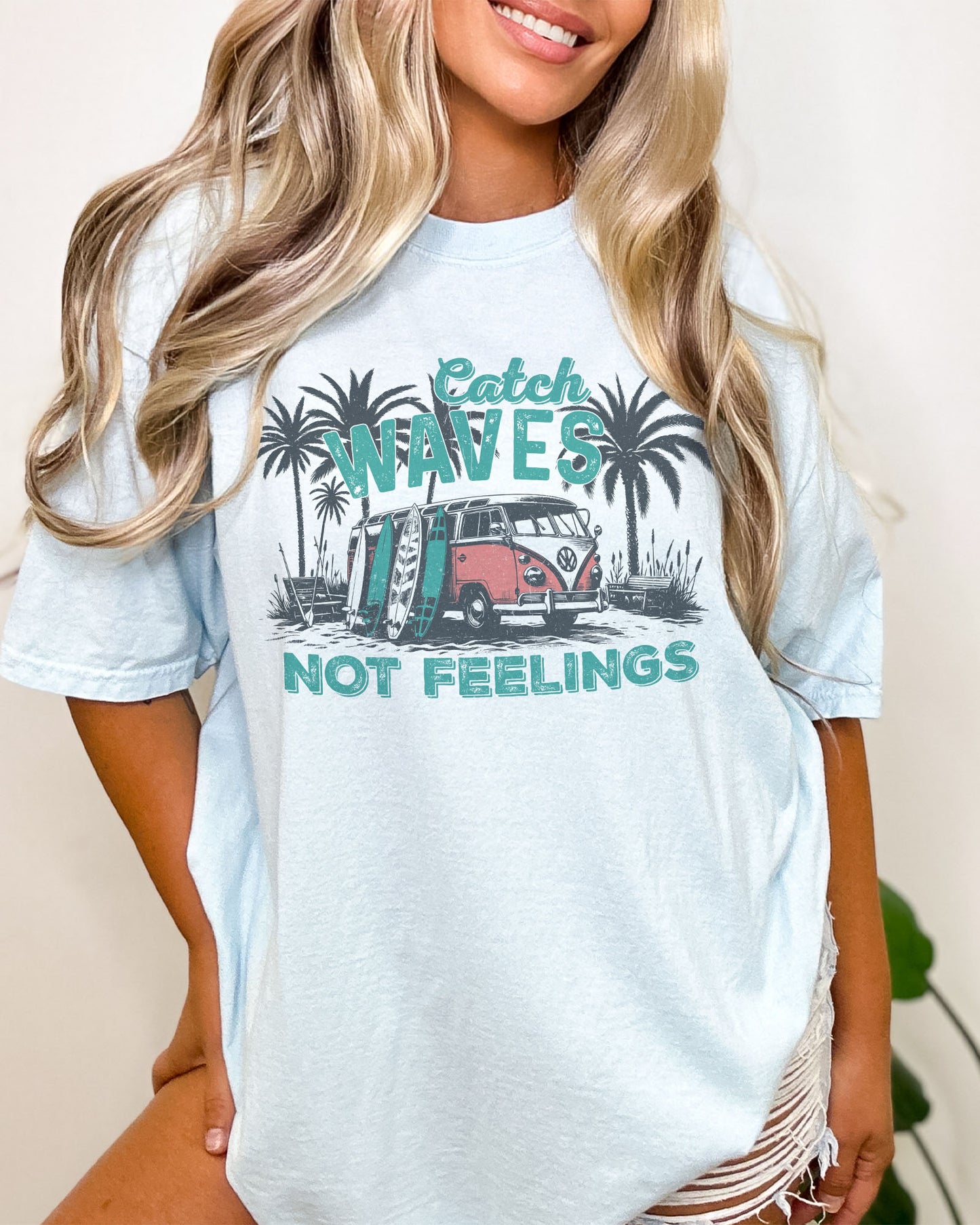 Model wearing chambray color shirt with 'Catch Waves Not Feelings' summer graphic design