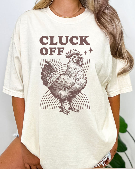 Woman wearing funny retro chicken graphic shirt in natural beige color with the quote "Cluck Off"