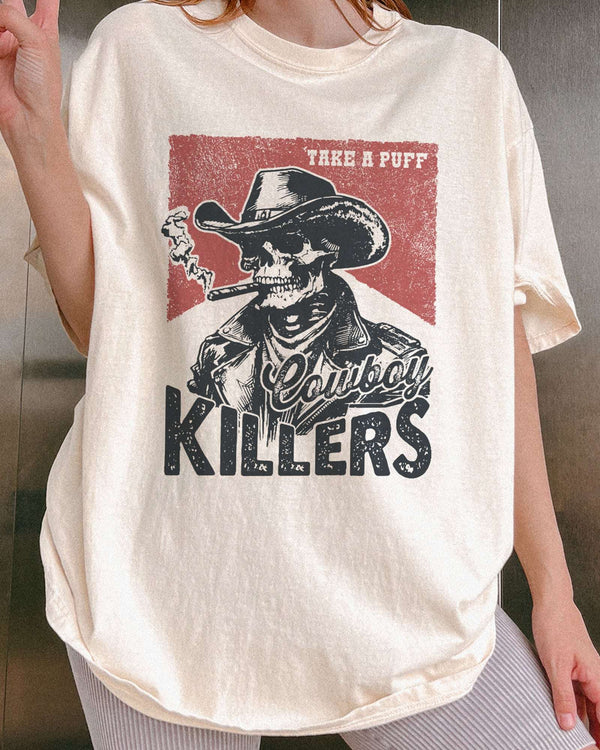 Close-up of model wearing ivory color shirt with 'Cowboy Killers' funny smoking skeleton graphic design