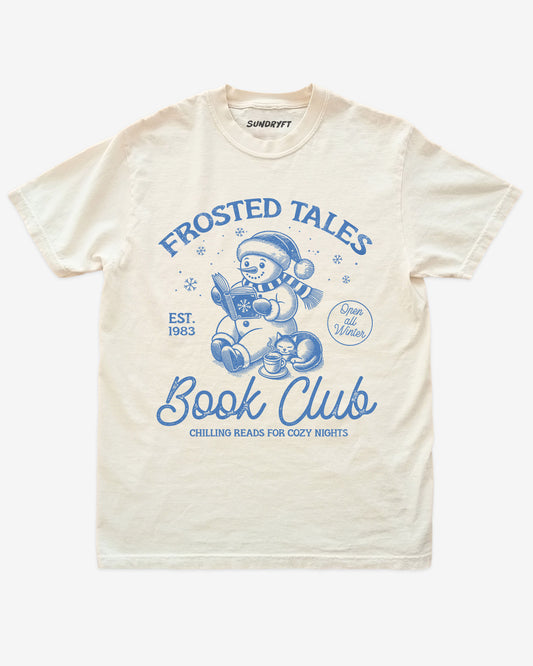 Ivory shirt with cute snowman reading book design and “Frosted Tales Book Club” text