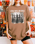 Woman wearing an espresso-colored “Girls Will Be Girls” shirt with a retro graphic of witches performing a witchy ritual.