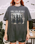 Woman wearing a pepper-colored “Girls Will Be Girls” shirt with a retro graphic of witches performing a witchy ritual.