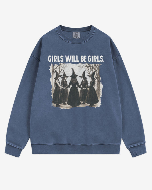 Flat lay denim 'Girls Will Be Girls' sweatshirt with retro graphic of witches holding hands in a Halloween ritual.