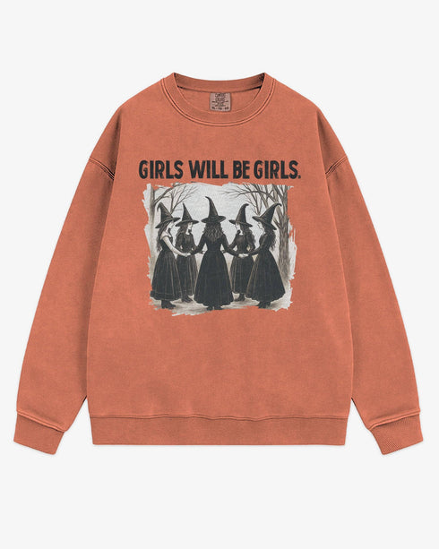 Flat lay terracotta 'Girls Will Be Girls' sweatshirt with retro graphic of witches holding hands in a Halloween ritual.