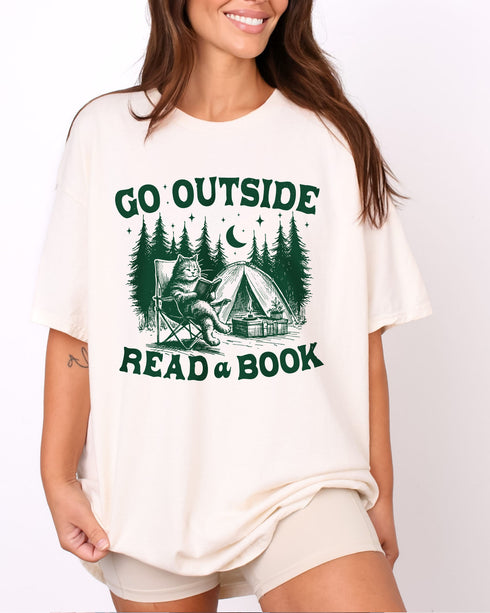 Model wearing natural color shirt with 'Go Outside Read A Book' graphic design