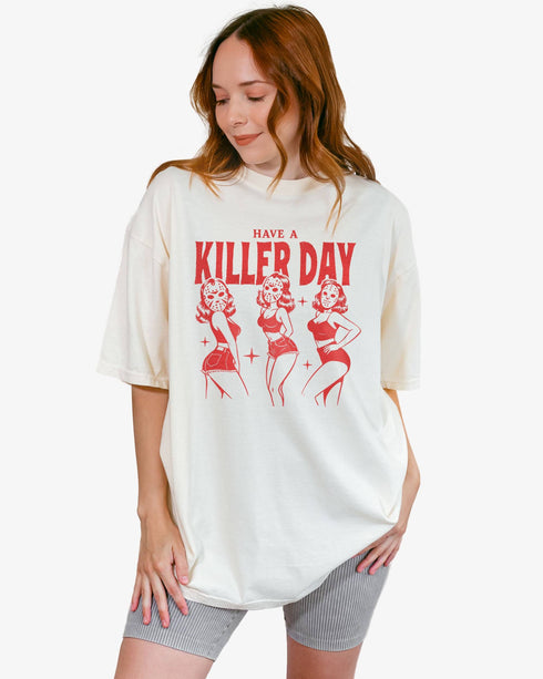 Woman wearing an ivory-colored “Have A Killer Day” shirt with a funny Halloween graphic of bikini girls in hockey masks.