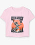 Woman wearing a light pink 'He Is Rizzin' baby tee featuring a funny retro Jesus playing basketball graphic, perfect for Y2K and Christian humor style.