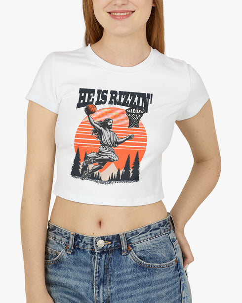 Woman wearing a white 'He Is Rizzin' baby tee featuring a funny retro Jesus playing basketball graphic, perfect for Y2K and Christian humor style.