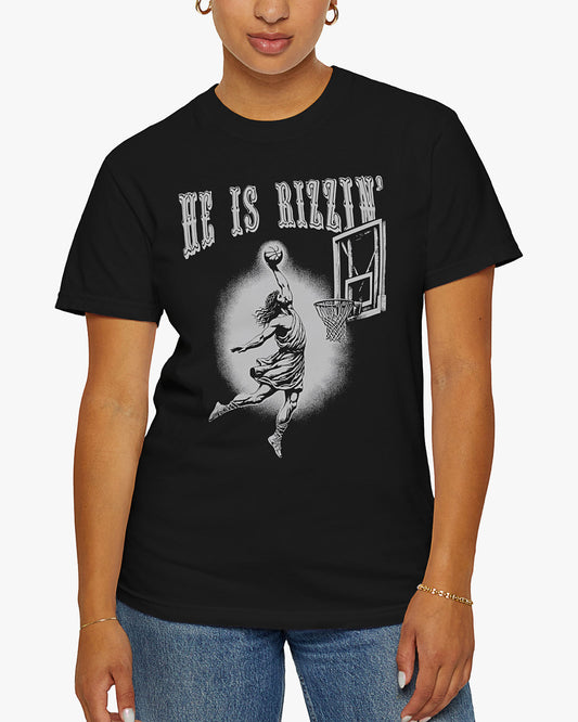 Woman is wearing He is Rizzin' tee in black color with funny Jesus dunking a basketball graphic