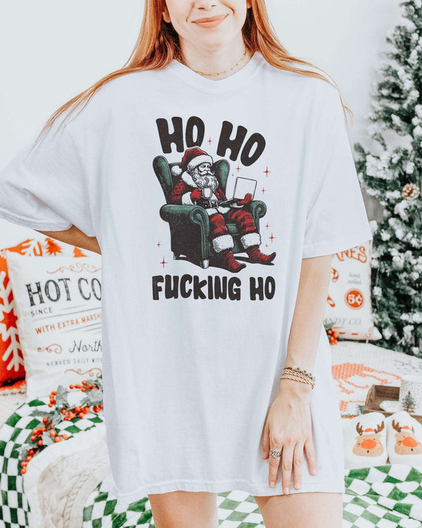 Woman wearing a white "Ho Ho Fucking Ho" shirt with a funny retro graphic of Santa Claus sitting in an armchair.