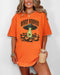 Woman wearing a burnt orange "Howdy Pumpkin" shirt with a retro graphic of a UFO abducting pumpkins from a field.