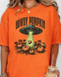 Close up of woman wearing a burnt orange "Howdy Pumpkin" shirt with a retro graphic of a UFO abducting pumpkins from a field.