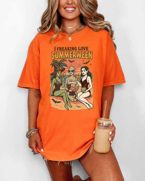 Woman wearing a burnt orange "I Freaking Love Summerween" shirt with a retro graphic of two witches and a mummy relaxing on the beach.