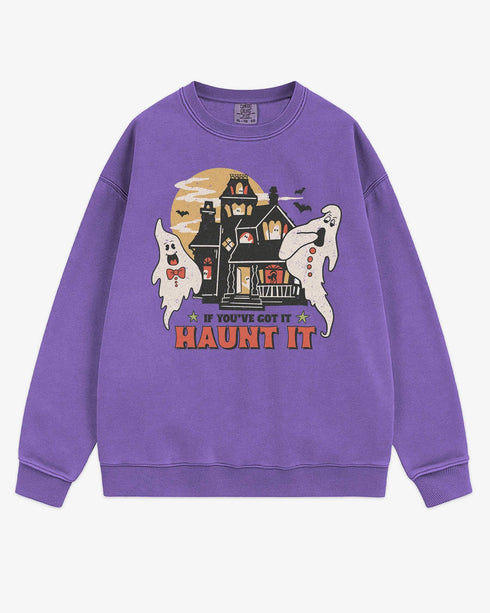 Flat lay violet sweatshirt with phrase ‘If You’ve Got It Haunt It’ and retro graphic of two ghosts and a haunted house.