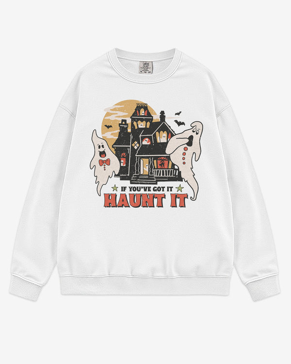 Flat lay white sweatshirt with phrase βIf Youβve Got It Haunt Itβ and retro graphic of two ghosts and a haunted house.