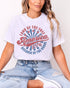 Model wearing ash color shirt with 'Land Of The Free Because Of The Brave' graphic design