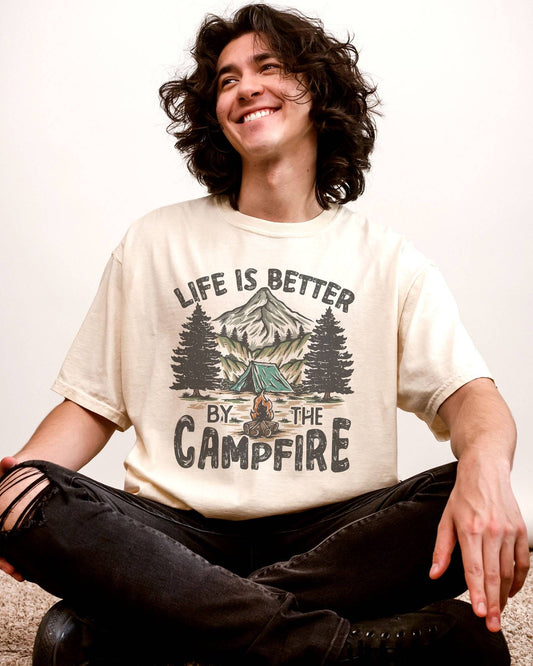 Man wearing 'Life Is Better By The Campfire' shirt in ivory color and with retro camping nature graphic