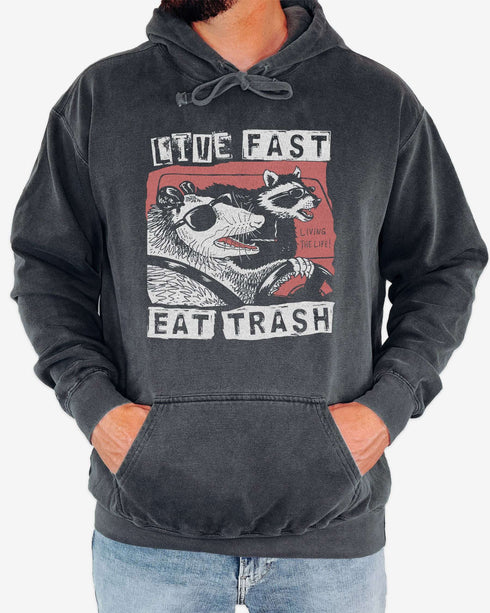 Man wearing pepper 'Live Fast Eat Trash' hoodie with a funny retro graphic of two raccoons driving a car.