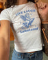 Woman wearing white baby tee with text "Live Laugh Lobotomy" and funny retro graphic of angel riding a rocket