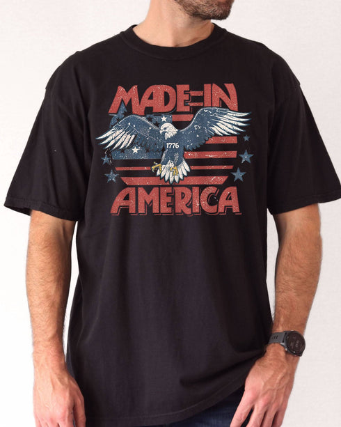 Man wearing "Made In America 1776" shirt in black color with retro graphic of a hawk in USA red-white-and-blue colors.