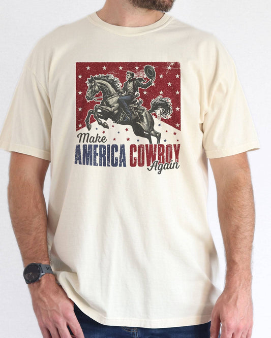 Model wearing natural color shirt with 'Make America Cowboy Again' graphic design