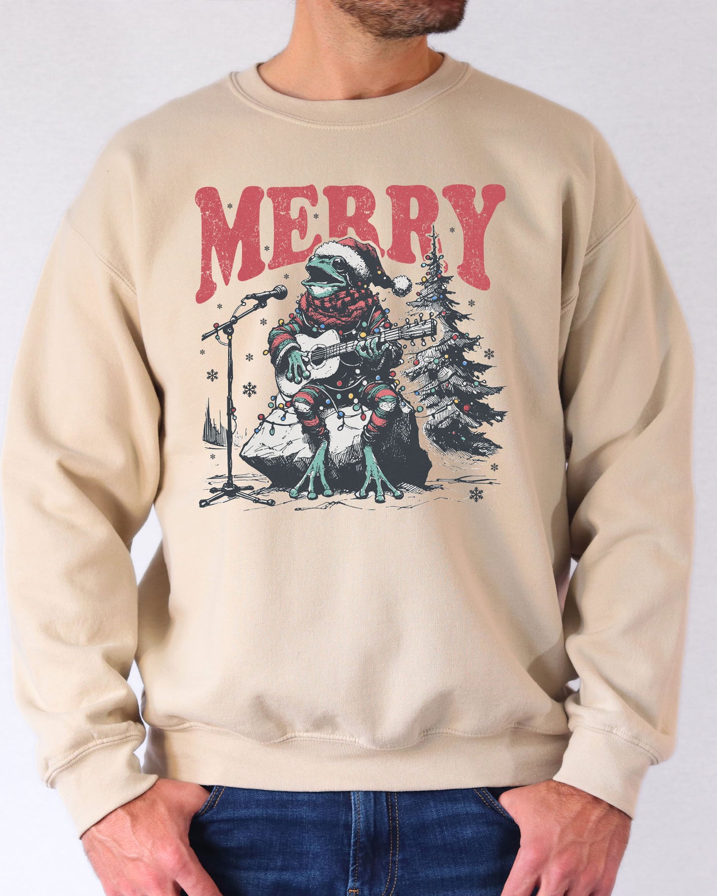 Model wearing sand color sweatshirt with 'Merry Frog' graphic design