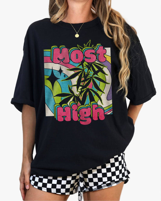 Woman wearing a black ‘Most High’ shirt with a retro multicolor trippy collage graphic of cannabis plants.