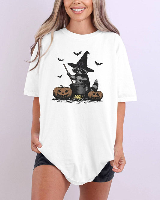 Model wearing white color shirt with 'Halloween Raccoon Witch' graphic design