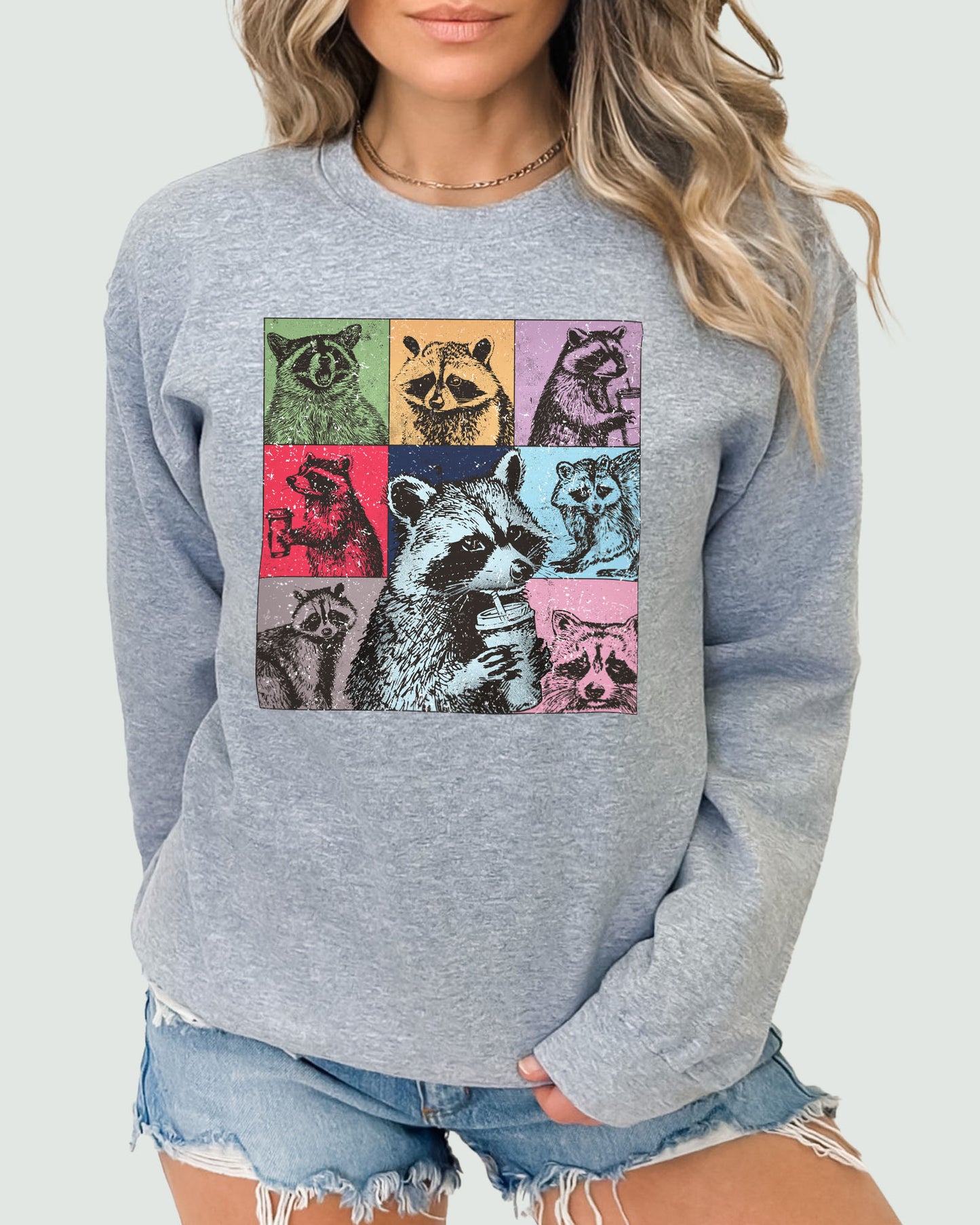 Woman wearing a sweatshirt in sport gray, featuring a retro raccoons drinking coffee collage graphic design and unisex fit.
