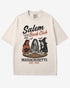 Flat lay ivory-colored 'Salem Book Club Massachusetts 1692' shirt with retro Halloween graphic of a devil, skeleton, and witch sitting together reading at a table.