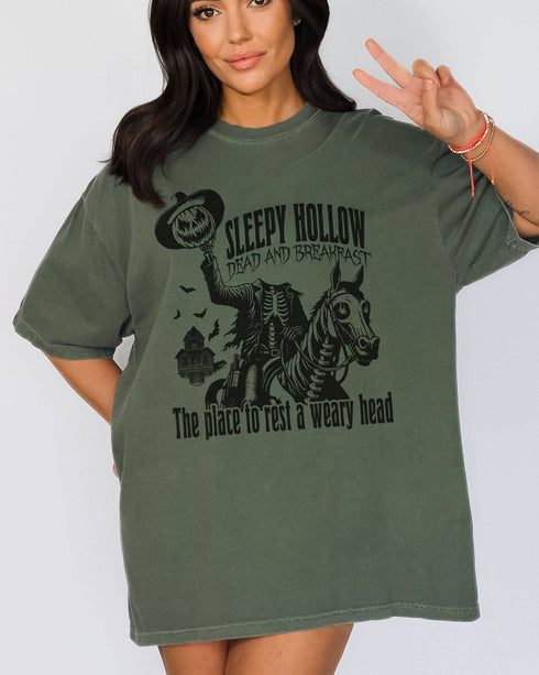Model wearing moss color shirt with 'Sleepy Hollow Dead And Breakfast - The Place To Rest A Weary Head' graphic design