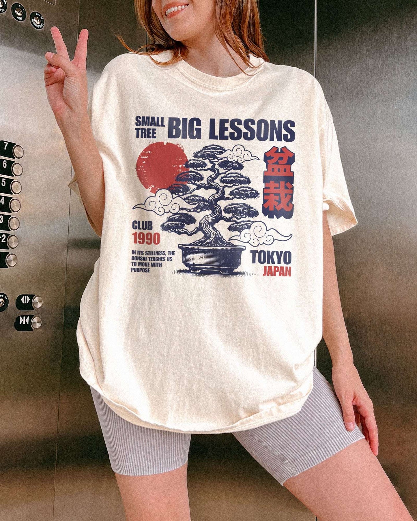 Woman wearing an ivory Small Tree Big Lessons Bonsai shirt with a retro Tokyo-inspired bonsai graphic.
