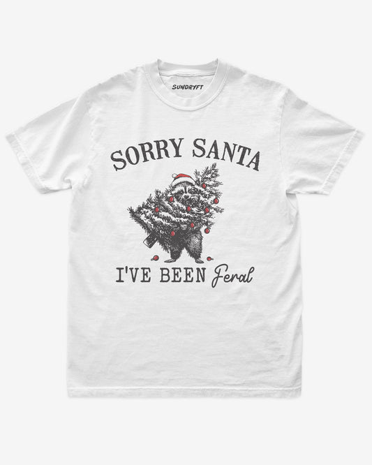 Sorry Santa I've Been Feral shirt in white with raccoon eating Christmas tree graphic