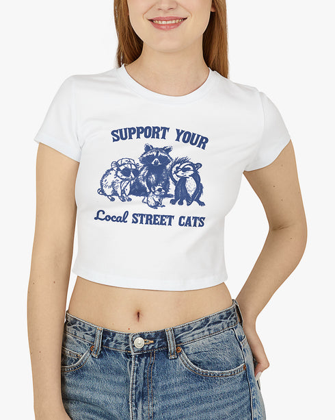Woman wearing white 'Support Your Local Street Cats' baby tee with funny retro racccoon and opossum graphic