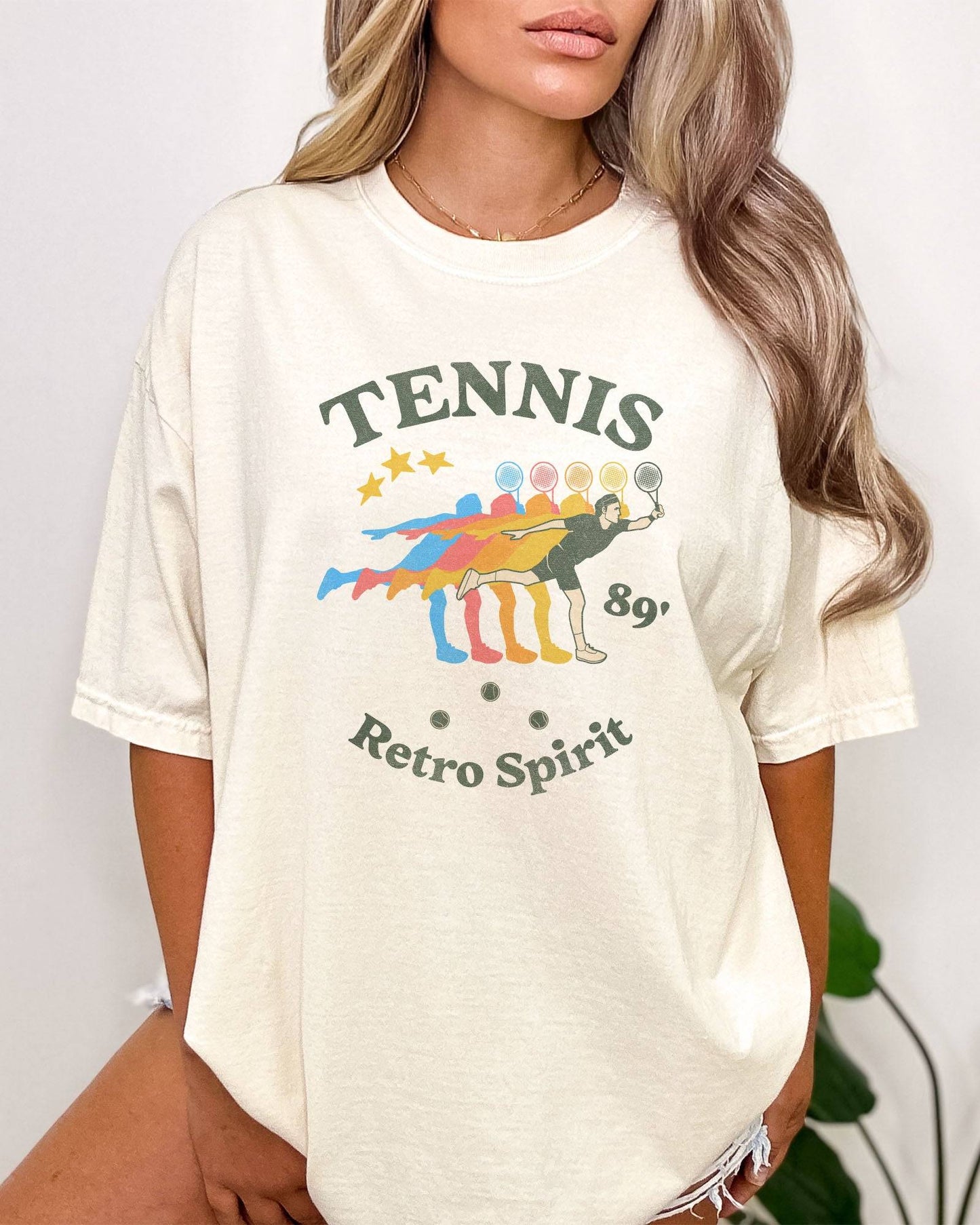 Woman wearing "Tennis 89' Retro Spirit" shirt in ivory color with a vintage tennis player graphic.
