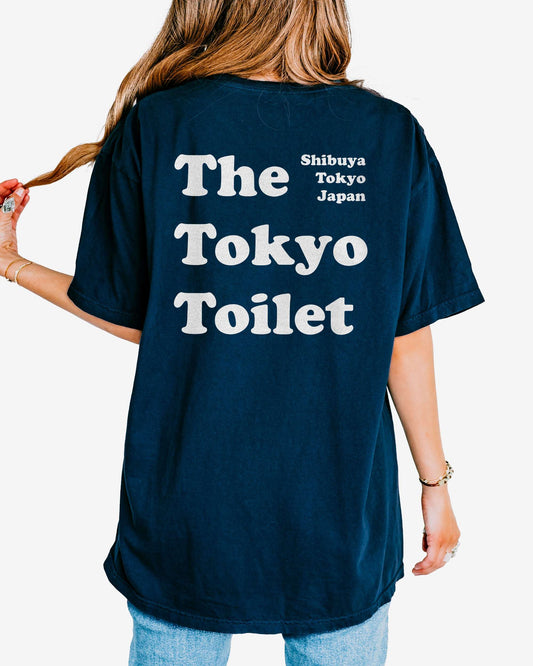 Woman wearing a true navy T-shirt with 'The Tokyo Toilet' text printed on the back, inspired by Shibuya's public toilets.