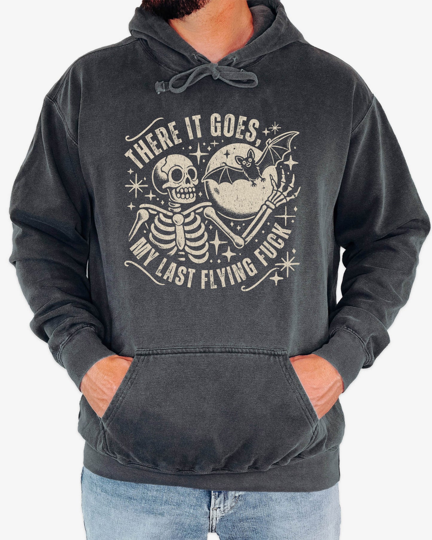 Man wearing pepper 'There It Goes My Last Flying Fuck' hoodie with funny retro skeleton and bat Halloween graphic.