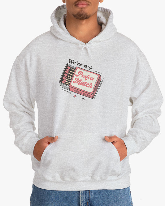 Man wearing ash gray 'We're A Match' hoodie with retro matchbox valentine's Day graphic