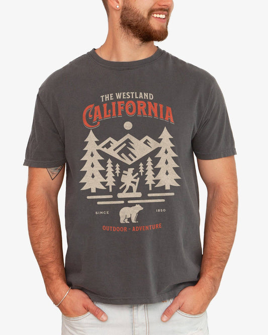 Man wearing a pepper Westland California Outdoor Adventure shirt with a retro vector graphic of a hiker, bear, and mountains.