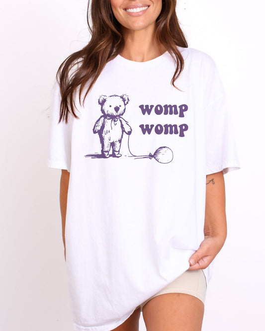 Model wearing white color shirt with 'Womp Womp' graphic design
