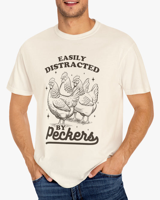 Man wearing a 'Easily Distracted By Peckers' shirt in natural beige, featuring a retro chicken graphic design and unisex fit.