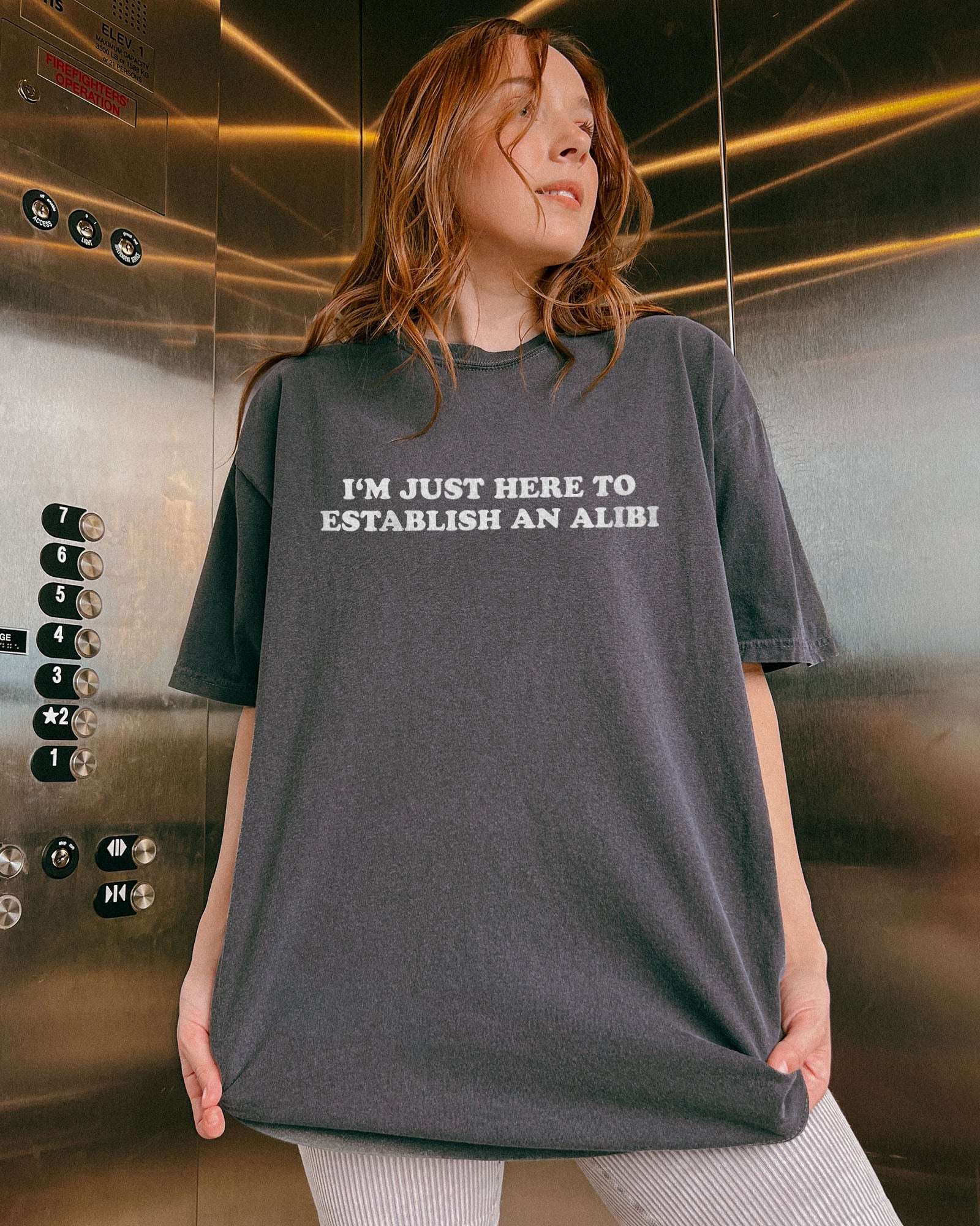 Woman wearing a pepper I'm Just Here To Establish An Alibi shirt.